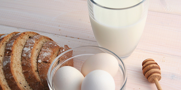 Bread, milk, eggs, and honey on countertop
